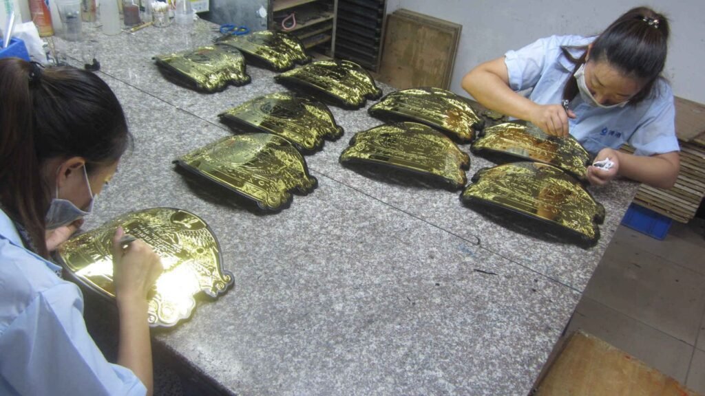 Worker inspecting gold plated metal gifts against a colour reference tray